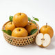 Jumbo Korean pears with golden amber speckled skin in a bamboo basket, one cut in half showing crisp white juicy flesh