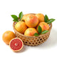 Fresh ruby red grapefruit in a bamboo basket with one cut in half showing pink citrus flesh